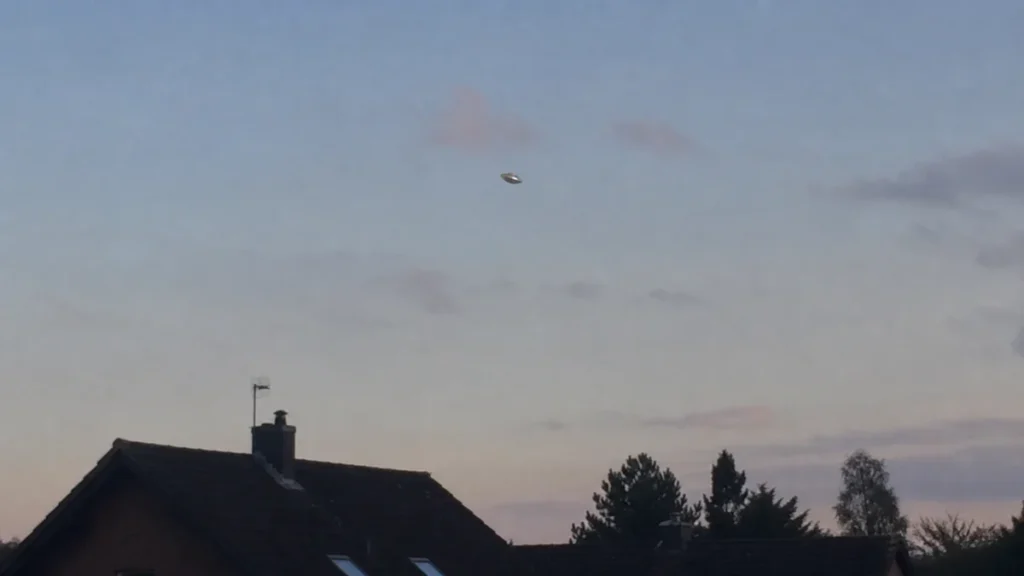 Unscharfe scheibenförmige Erscheinung am Abendhimmel über Hausdächern