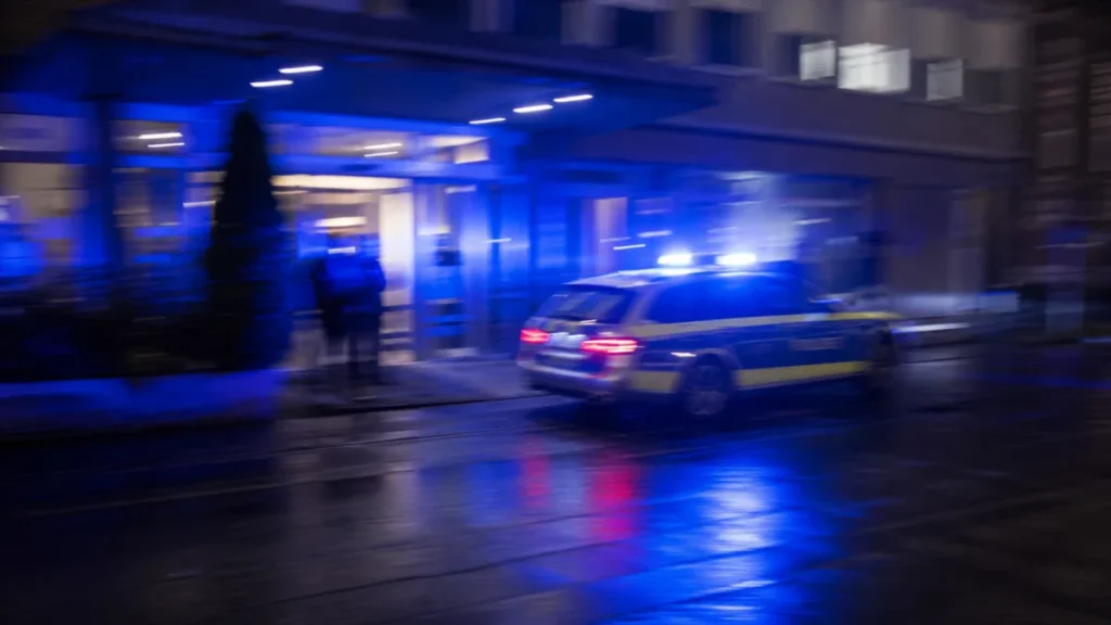 Nächtlicher Polizeieinsatz vor einem Hotel mit starkem Blaulicht und Bewegungsunschärfe