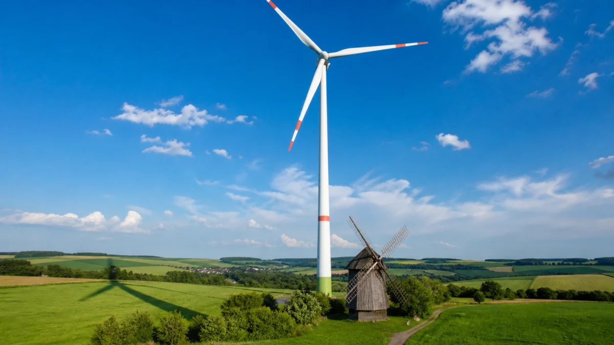 Symbolbild: Ein modernes Windrad überragt eine historische Windmühle