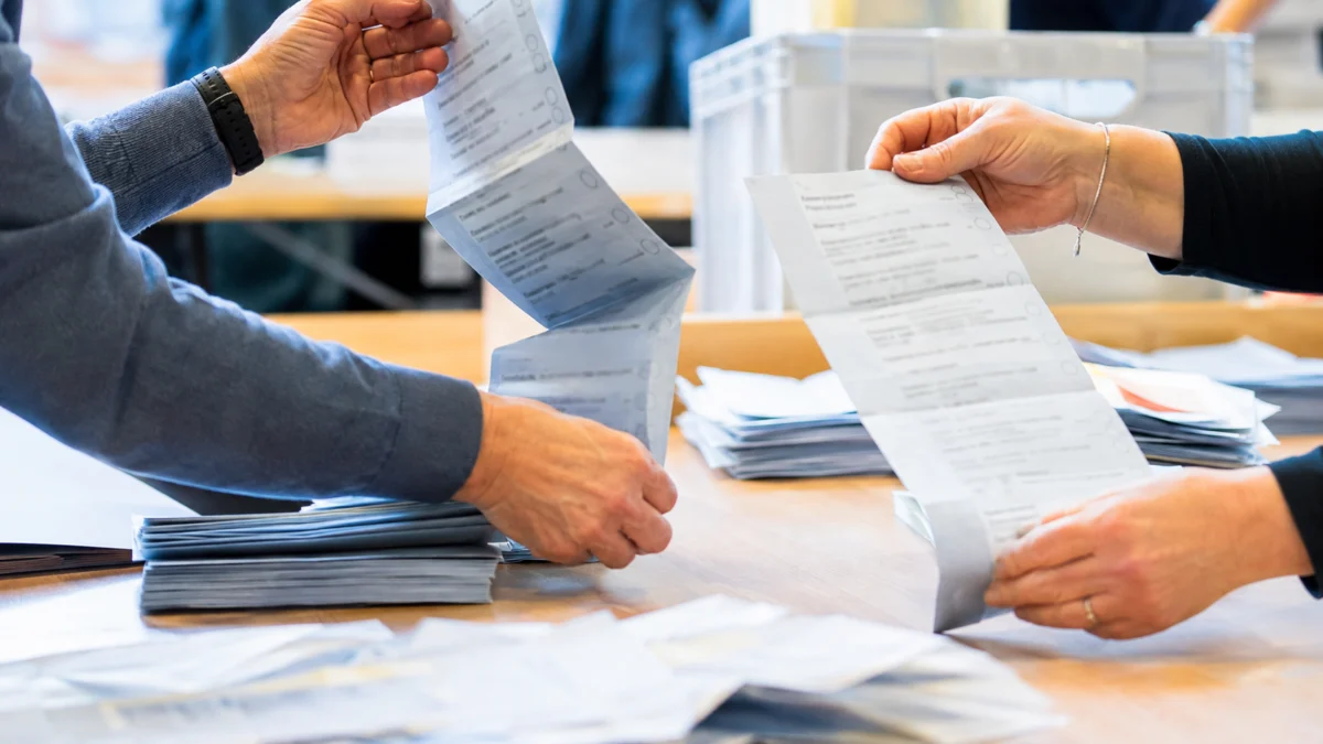 Hände von Wahlhelfern beim Nachzählen von Stimmzetteln